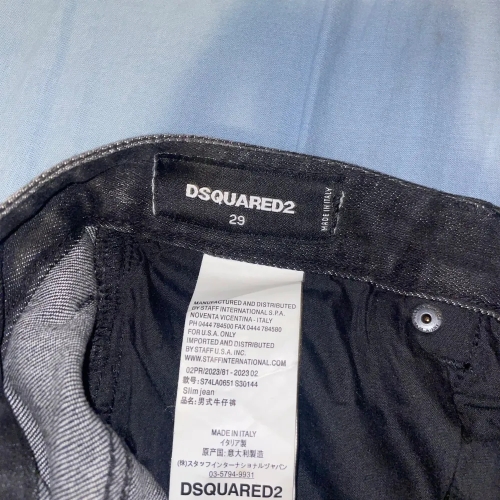 Säljer ett par svarta Dsquared2 jeans i slim fit. De har en cool distressed look med färgstänk och slitningar som ger en edgy stil. Perfekta för både vardag och fest.. Jeans & Byxor.