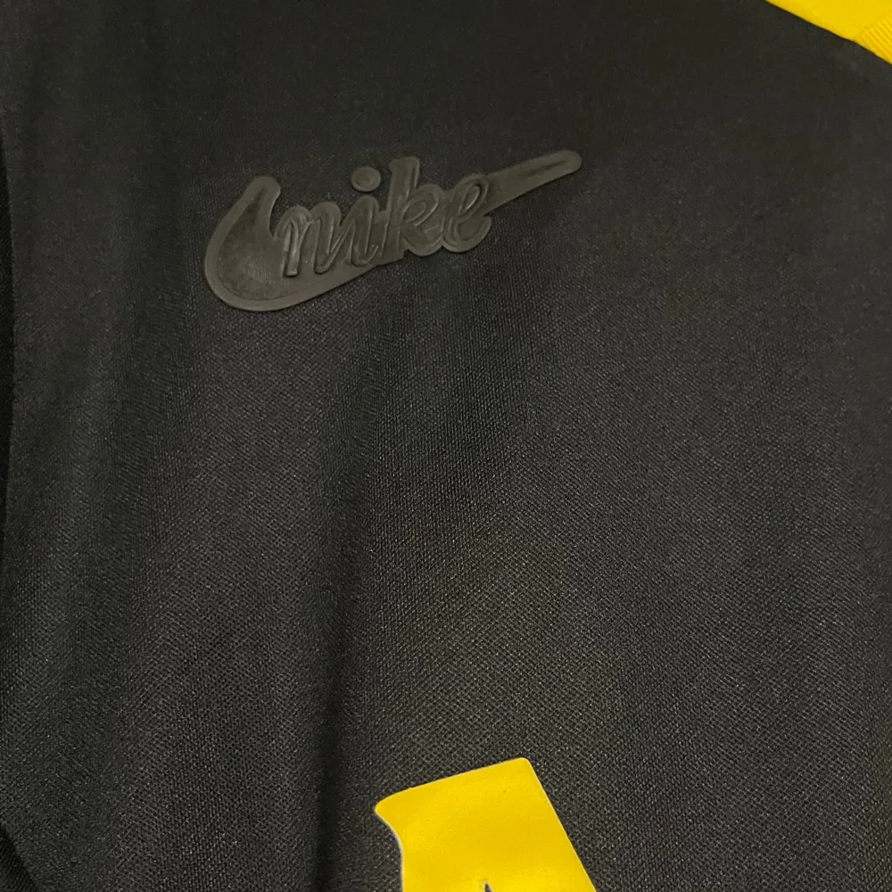 Säljer en svart långärmad AIK-tröja från Nike i storlek XXL. Tröjan har gula detaljer och texten 'AIK' på framsidan. Perfekt för fans som vill visa sitt stöd med stil. Tröjan är i mycket bra skick och har en snygg design med klubbens emblem från 1924.. T-shirts.