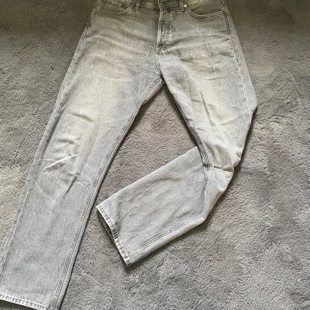 Säljer ett par grå jeansbyxor i bra skick. De har en klassisk femficksdesign och en rak passform. Perfekta för både vardag och fest! . Jeans & Byxor.