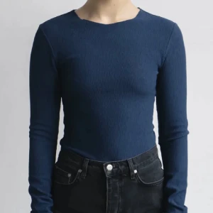 Mörkblå ribbad tröja A-DSGN - Säljer en stilren mörkblå ribbad tröja med långärmad design. Perfekt för både vardag och festliga tillfällen. Tröjan har en tight passform som framhäver figuren och är gjord i ett mjukt och bekvämt material. Ett måste i garderoben för alla säsonger! Helt slutsålt på butikens webbplats! Tröjans storlek är M men passar även för nån som har storlek S 🫶🏻