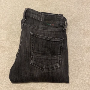 Svarta jeans i bra skick - Säljer ett par svarta jeans efterfrågade och limiterade Jack & Jones jeans i bra skick. De har en snygg, tvättad look och är perfekta för både vardag och fest. Jeansen är slim fit och är tillverkade i ett bekvämt denimtyg. Jeansen är i storlek W29 L30 men skulle rekommendera jeansen för dig som har en storlek mindre