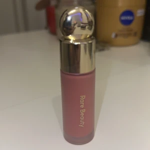 Rare Beauty flytande rouge i nyansen Hope - Säljer en flytande rouge från Rare Beauty i nyansen Hope. Den kommer i en söt liten flaska med guldfärgat lock och rymmer 7,5 ml alltså full size. Testad två gånger och inte rört huden direkt köpt för 389 säljer den för 200