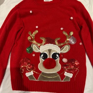 Röd jultröja med renmotiv från KappAhl - Superfin röd jultröja från KappAhl med ett gulligt renmotiv. Tröjan har långa ärmar och är dekorerad med glittriga detaljer och små bollar. Perfekt för julfirandet och den är i storlek 158/164. Storleken passar en som har xs också