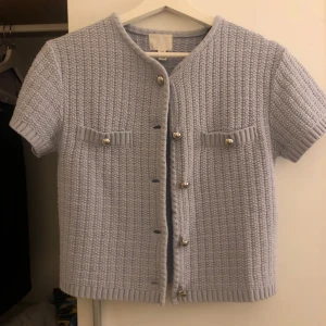 Ljusblå stickad kofta - Säljer en superfin ljusblå stickad kofta med korta ärmar och snygga knappar framtill. Den har två dekorativa fickor på bröstet med knappar. Perfekt för vår och sommar, och ger en chic touch till vilken outfit som helst! Har använt den Max 2 gånger och inte mer då jag känner att de inte är ritkigt i min stil. Priset går även att diskuteras💞nY pris 300kr. 