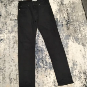 Svarta jeansbyxor - Snygga svarta jeansbyxor med en klassisk design. De har en rak passform och är perfekta för en stilren look. Byxorna har fickor fram och bak samt knappar i midjan.