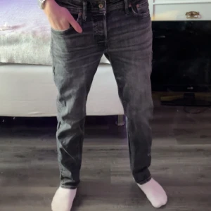 Svarta jeans från Jack & Jones - Snygga svarta/grå jeans från Jack & Jones med en klassisk design. De har en rak passform och är tillverkade i ett slitstarkt denimtyg. Perfekta för en stilren look. 31/32