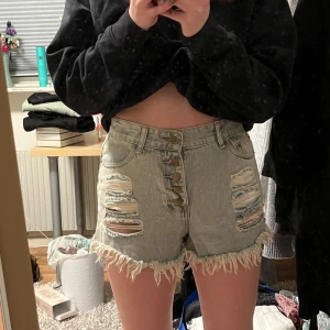 Ljusa jeansshorts med slitningar - Snygga ljusa jeansshorts med slitna detaljer och fransig kant. Shortsen har en knappgylf med flera knappar och klassiska femficksdesign. Perfekta för en avslappnad stil.
