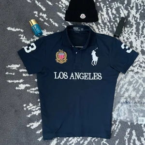 Mörkblå pikétröja från Ralph Lauren cheif keif y2k 2000s  - Snygg mörkblå pikétröja från Ralph Lauren med broderad logga och texten 'LOS ANGELES' på framsidan. Tröjan har korta ärmar och en klassisk krage med knappar. Perfekt för en stilren look. Cheif keif style y2k 