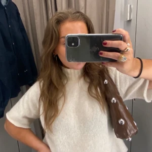 Vit stickad tröja - Säljer en stilren vit stickad tröja med korta ärmar. Perfekt för en avslappnad och trendig look. Tröjan har en hög krage som ger extra värme och stil.