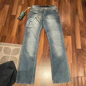 lowwaist jeans - Snygga blå jeans från GF Ferre med unika detaljer och broderier på bakfickorna. Jeansen har en straight passform och är dekorerade med märkets logga. Perfekta för en stilren look.