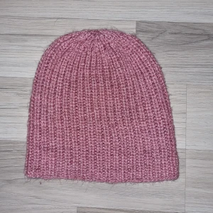 Rosa stickad mössa - Säljer en mysig rosa stickad mössa. Perfekt för kyliga dagar med sin ribbade design som ger en skön passform. Enkelt och stilrent plagg som passar till det mesta. Mössan är hemmastickade.