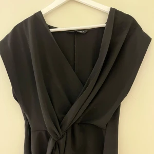 Svart omlottopp från Zara - Snygg svart omlottopp från Zara i en elegant design. Toppen har en v-ringad hals och knytning i sidan. Köpt för 300 och är aldrig använd utan mig och köptes med nyskick så den har väldigt bra skick ser ny ut.