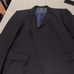 Mörkblå kavaj från Berkeley - Snygg mörkblå kavaj från Berkeley, perfekt för formella tillfällen. Tillverkad av 100% ull med ett elegant randigt foder. Klassisk design med knappar framtill och fickor med lock. En stilren och tidlös kavaj för garderoben.