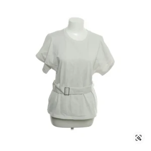 Vit t-shirt med bälte - Säljer en stilren vit t-shirt med korta ärmar och ett matchande bälte i midjan. Toppen är från Zara, i storlek S och har en snygg passform som drar in midjan.