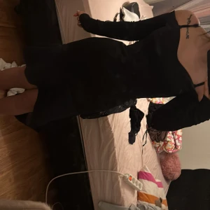 Svart klänning med öppen rygg - Snygg svart klänning med öppen rygg och långa ärmar. Perfekt för en kväll ute eller en speciell tillställning. Klänningen har en elegant passform och är tillverkad i ett mjukt material som ger en bekväm känsla. Den är oanvänd 