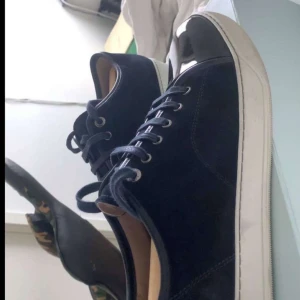 Lanvin - Snygga blå sneakers från Lanvin med glansiga lackdetaljer på tån. Skorna har en klassisk snörning och en vit sula som ger en stilren kontrast. Perfekta för en trendig look. Vid fler frågor är du välkommen att höra av dig!