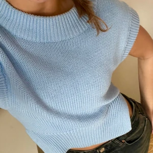 Ljusblå stickad topp - Säljer en jättefin ljusblå stickad topp med korta ärmar och ribbad nederkant. Toppen är croppad och har en avslappnad passform.