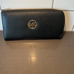 Svart plånbok /kuvert väska  - Snygg svart plånbok /kuvertväska i skinn med dragkedja runtom draghållere är bortta men funkar . Den har flera fack för kort och en innerficka med logotypmönster. Perfekt för att hålla ordning på dina kort och kontanter.