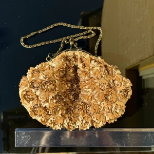 Beige / rosa blommig väska med kedja - Superfin beige /rosa väska med blommigt mönster. Väskan har en  kedja som axelrem och är perfekt för festliga tillfällen. Den är dekorerad med vackra blommor som ger en romantisk touch. Mått -se linjal på bild. Hämtas på Hägerstensåsen eller ök 💖