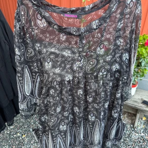 Mönstrad transparent topp från Indiska - Säljer en superfin mönstrad topp från Indiska. Den är svart med ett vitt och grått paisleymönster. Toppen är transparent och har trekvartsärmar, perfekt för en somrig look eller att ha över ett linne. Den är i nyskick och passar både till vardags och fest!