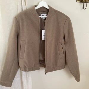 Bomberjacka - Beige fin bomberjacka från na-kd. Har aldrig använts (lappar kvar) nypris 799. Har lite axelvaddar