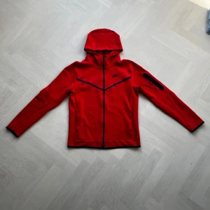 Nike tech fleece  - Säljer nu denna tech fleece i den röda färgen. Köpt på Nikes hemsida för ett par år sedan men har legat i garderoben efter ett fåtal användningar. Det är inga defekter eller fläckar på hoodien. Priset kan diskuteras vid snabb affär!