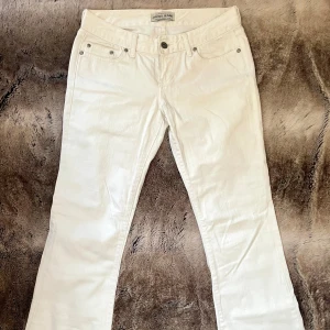 Vita lågmidjade bootcut jeans - Så himla snygga vita lågmidjade jeans! De var tyvärr för tighta på mig, så har inte kommit till användning alls. Mycket fint skick! Köpte som storlek M (W28 L32) Från Cross Jeans 🤍 midjemått: 36cm, mått från grenen och upp: 19cm, innerbensmått: 77cm 