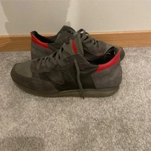 Philippe Model Trainers - Snygga sneakers i grått och rött med snörning. Skorna har en stilren design med en kombination av mocka och syntetmaterial. Perfekta för en avslappnad stil.