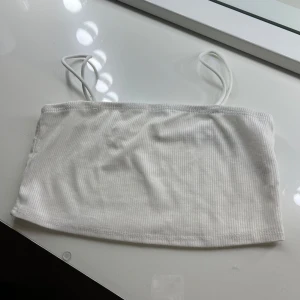 Vit ribbad kort topp från Shein - Säljer en stilren vit ribbad kort topp från Shein. Toppen har smala axelband och är perfekt för varma dagar. Enkel och snygg design som passar till det mesta. Perfekt för att skapa en avslappnad look. Den kostade 30 kr när jag köpte den. Den är aldrig använd men den är så fin. 😍