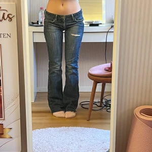 Bootcut jeans - Mörkblåa lågmidjade bootcut jeans från fornarina med blåa rhinestones på bakfickorna. Storlek 27 och avklippta längst ner (se sista bilden). Innerbenslängd 79 cm och midja rakt över 40 cm. Använd köp nu💞