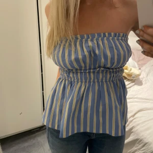Blå och gul randig tubtopp - Säljer en söt tubtopp i blått och gult med ränder. Toppen har en elastisk midja som ger en fin passform och en luftig nederdel. Perfekt för varma dagar❣️❣️
