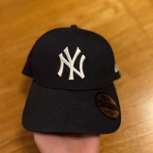 Svart keps med broderad logotyp - Snygg svart keps med vit broderad logotyp framtill. Justerbar passform med spänne baktill. Bara använd en gång🖤🥶