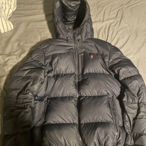 Ralph Lauren Jacka - Säljer min Ralph lauren jacka då den inte kommer till användning. Den är i super bra skick förutom en dragkedja på ena fickan (fungerar fof) och ett jätte litet hål vid ärmen som ej syns (kolla bilderna). Annars i perfekt skick. Pris kan diskuteras.