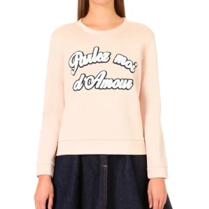 Beige maje sweatshirt med fransk broderad text - Säljer en beige sweatshirt från maje med texten 'Parlez moi d'Amour' i svart och vitt på framsidan. Tröjan har långa ärmar och en rund halsringning. Perfekt för en avslappnad stil.