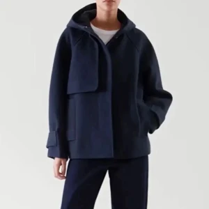 Mörkblå kappa från COS - Säljer en stilren mörkblå kappa från COS. Jackan har en minimalistisk design med knappar framtill och långa ärmar. Perfekt för en elegant look. Nypris var runt 2200 (minns ej exakt)