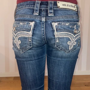 Bootcut rock revival jeans - Snyggaste jeanen från rock revival. Boocut och low waist. I fint skick förutom lite slitningar (ses på bilderna). Midjemåttet rakt över är 35cm. De är långa på mig som är 164. 