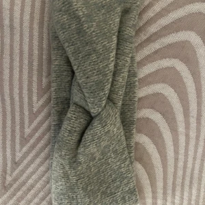 Grått pannband  - Snyggt grått pannband med en twistad design. Perfekt för att ge en stilren touch till din outfit. Tillverkat i ett mjukt material som sitter bekvämt hela dagen.