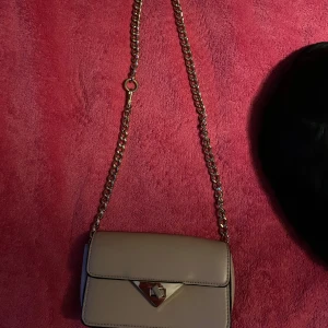 Beige axelväska med kedja, H&M - Snygg beige axelväska med guldfärgad kedja från H&M. Använd fåtal gånger. Plats för kort i.