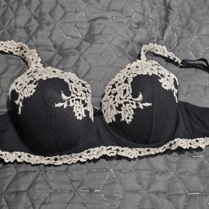 Svart intimissimi bh med spetsdetaljer - Elegant svart intimissimi bh med vacker vit spetsdetaljering. Den har justerbara axelband och en klassisk hakknäppning bak. Perfekt för en stilfull look. Jag är inte säkert på storleken för att nummer lappen är borta men den passar till 75D. 