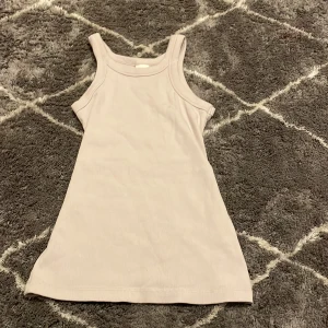 Beige ribbad linnetopp från H&M - Säljer en stilren beige ribbad linnetopp från H&M. Perfekt för en enkel och bekväm look. Toppen är ärmlös och har en klassisk design som passar till många olika outfits.