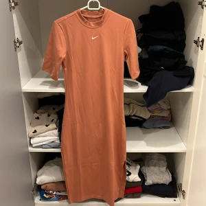 Rostfärgad klänning från Nike - Snygg rostfärgad klänning från Nike med korta ärmar och en enkel design. Perfekt för en sportig och avslappnad stil. Klänningen har en liten Nike-logga på bröstet, perfekt för sommaren. Orginal priset var 600kr ☀️