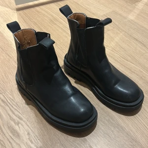 Svarta chelsea boots - Snygga svarta chelsea boots i skinn med elastiska paneler på sidorna för enkel på- och avtagning. De har en robust sula som ger bra grepp och en stilren design som passar till många olika outfits. Jag upplever de små i storlek, därav säljs de. 