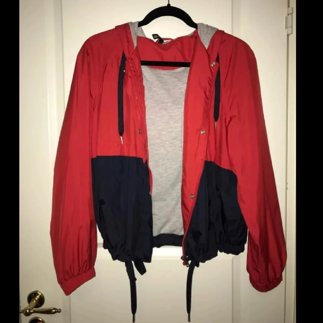 Röd och svart vindjacka med huva