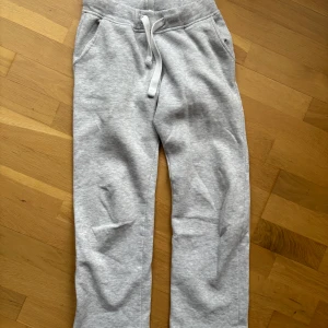 Grå mjukisbyxor med snörning - Säljer ett par bekväma grå mjukisbyxor med snörning i midjan. Byxorna har en loose passform och praktiska fickor på sidorna. Perfekta för en avslappnad stil.