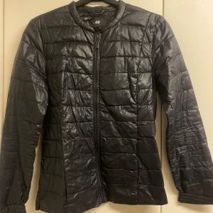 Mörkblå löparjacka från H&M - Snygg jacka från H&M med dragkedja framtill. Jackan har en stilren design med långa ärmar och en rund halsringning. Perfekt för kyligare löpturer