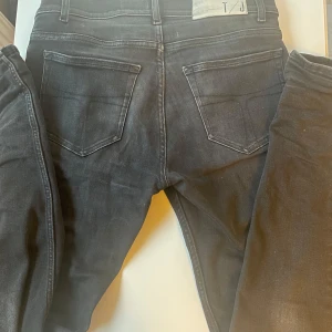 Svarta jeans från T/J - Snygga svarta jeans från T/J med en klassisk design. De har en normal passform och är tillverkade i ett slitstarkt material. Perfekta för en stilren look till ett suveränt pris!