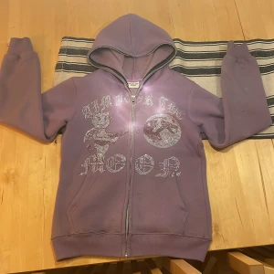 Aim for the moon hoodie - Säljer en lila hoodie med dragkedja och huva. Framsidan har texten 'aim for the Moon' dekorerad med glittriga paljetter. Perfekt för en avslappnad stil med en touch av glamour. Hör av dig vid intresse! 