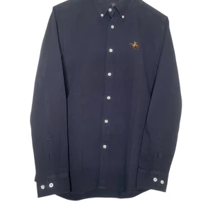 Purple label Ralph Laurel skjorta  - Ralph Lauren Purple Label skjorta i storlek S. Elegant och tidlös design i mörkblå färg, tillverkad av lyxiga, högkvalitativa material. Skjortan är i nyskick utan några synliga tecken på användning. Perfekt för både formella och semiformella tillfällen, med en passform och stil som speglar Purple Labels exklusivitet. Ett måste för den stilmedvetne!