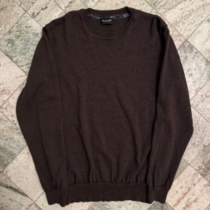 Långärmad från Sand Copenhagen - Säljer en stilren brun tröja från Sand Copenhagen. Tröjan har långa ärmar och en rund halsringning med ribbade muddar vid ärmslut och nederkant. Perfekt för en avslappnad och elegant look.