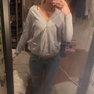 Ljusblå kofta  - Säljer en ljusblå kofta från Milk Copenhagen. Den har en v-ringad design med knappar framtill och långa ärmar. Finns små fläckar vid ärmen. P